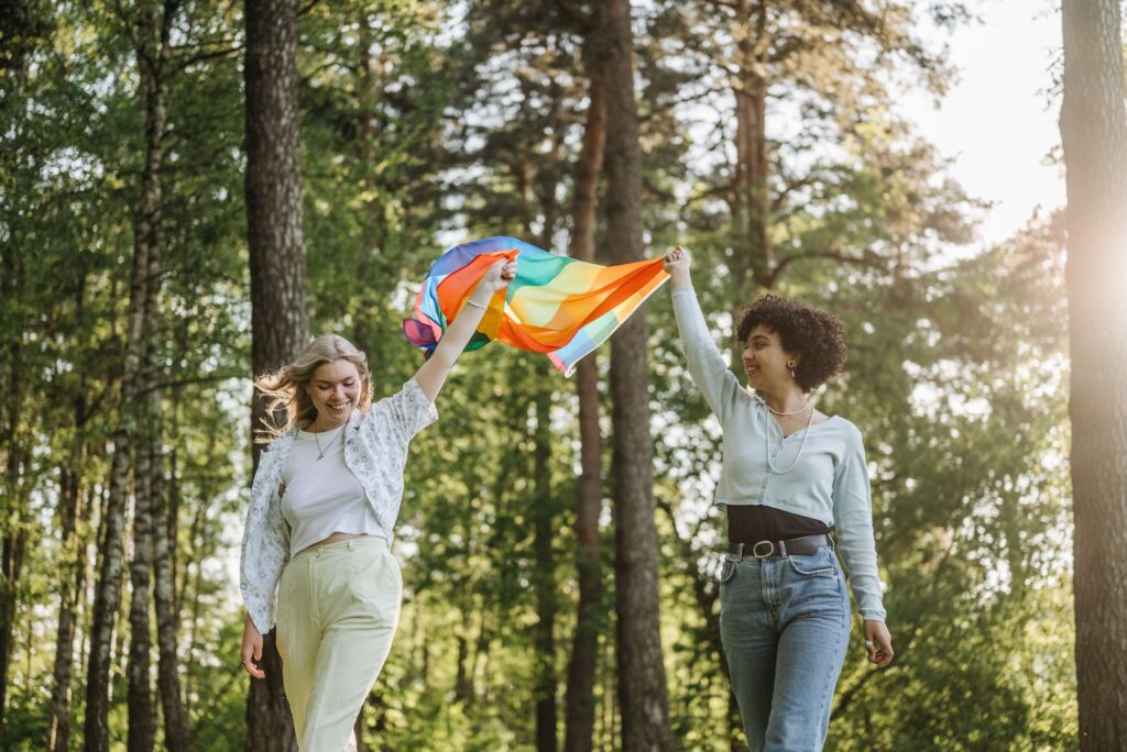 Two women carrying the pride flag in their hands